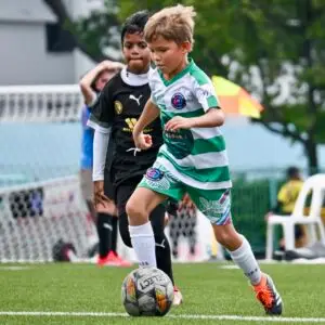 kids playing SYL football match Singapore Youth League academy team demonstrating football skills and dribbling from structured academy training session